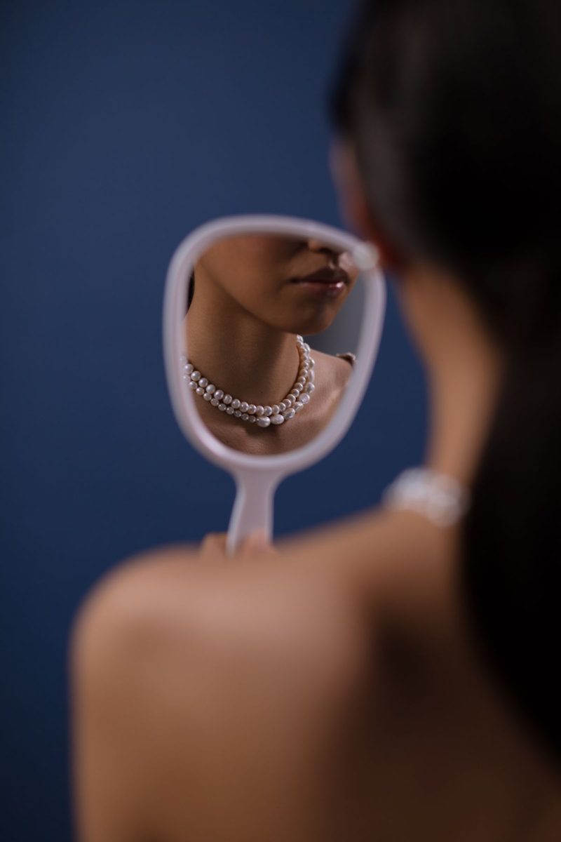 Woman with pearl necklace in a hand mirror